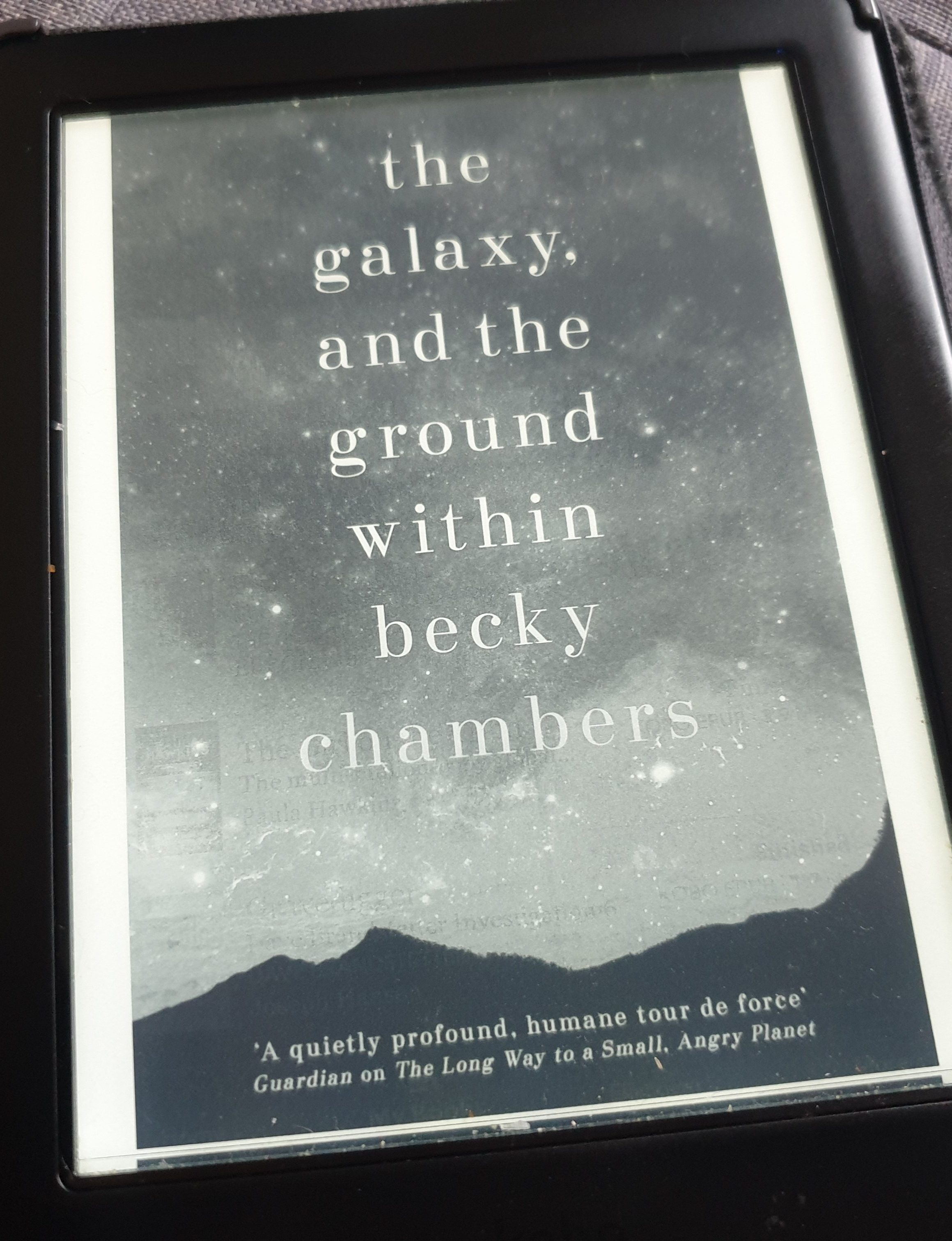 My ereader showing the cover of The Galaxy and the Ground Within by Becky chambers. It shows the title above a planet. 