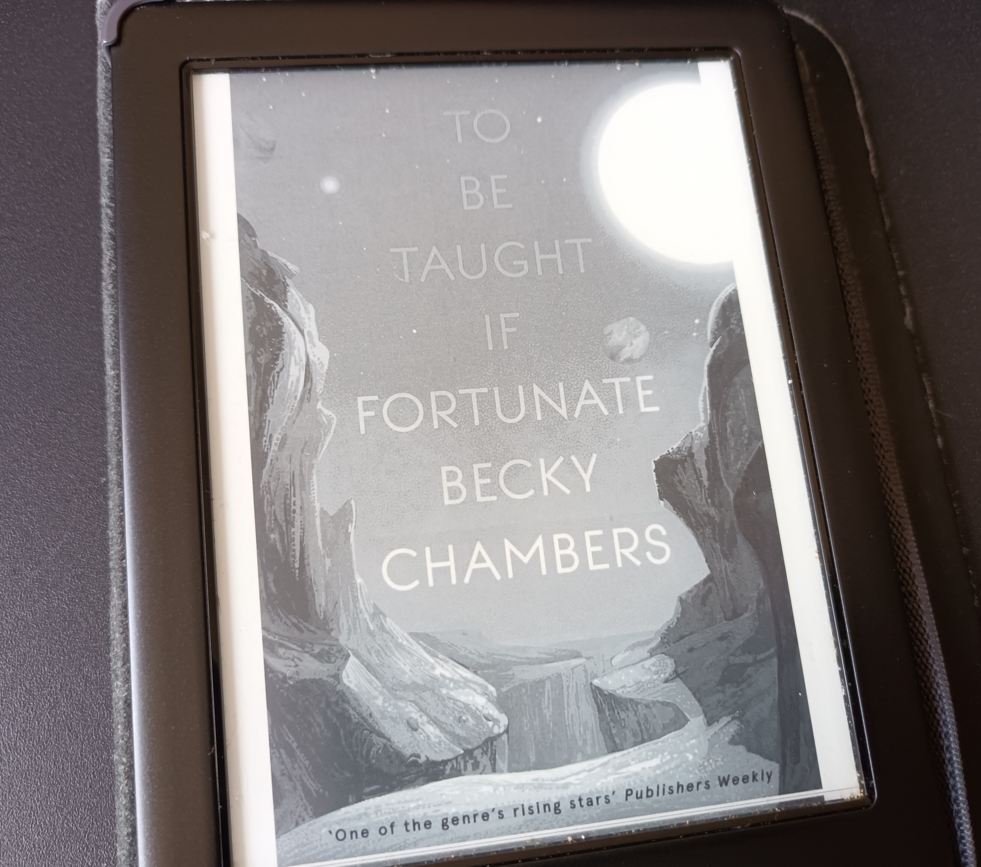 My ereader showing the cover of To be Taught if Fortunate by Becky chambers. It shows the title above a rocky planet landscape. 