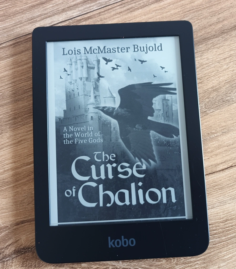 My e-reader showing the cover of The Curse of Chalion by Lois McMaster Bujold. It features a crow in the foreground with a flock of crows around a castle in the background. 